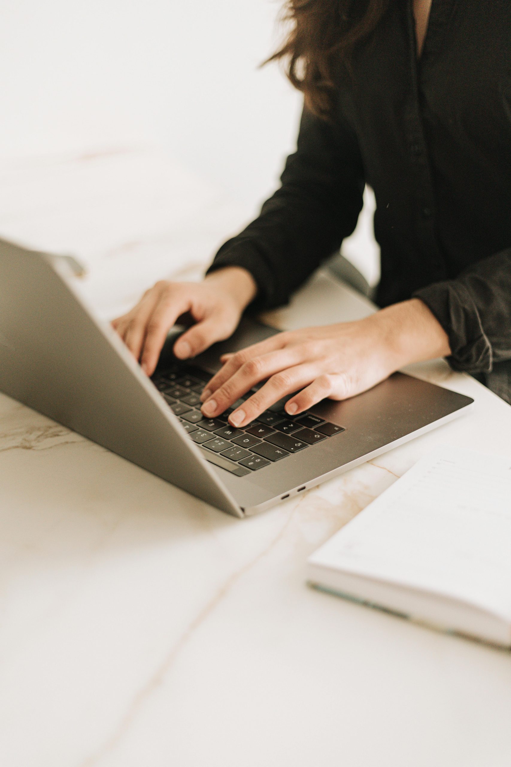 Woman typing on laptop in bright, modern workspace. Ideal for business settings.