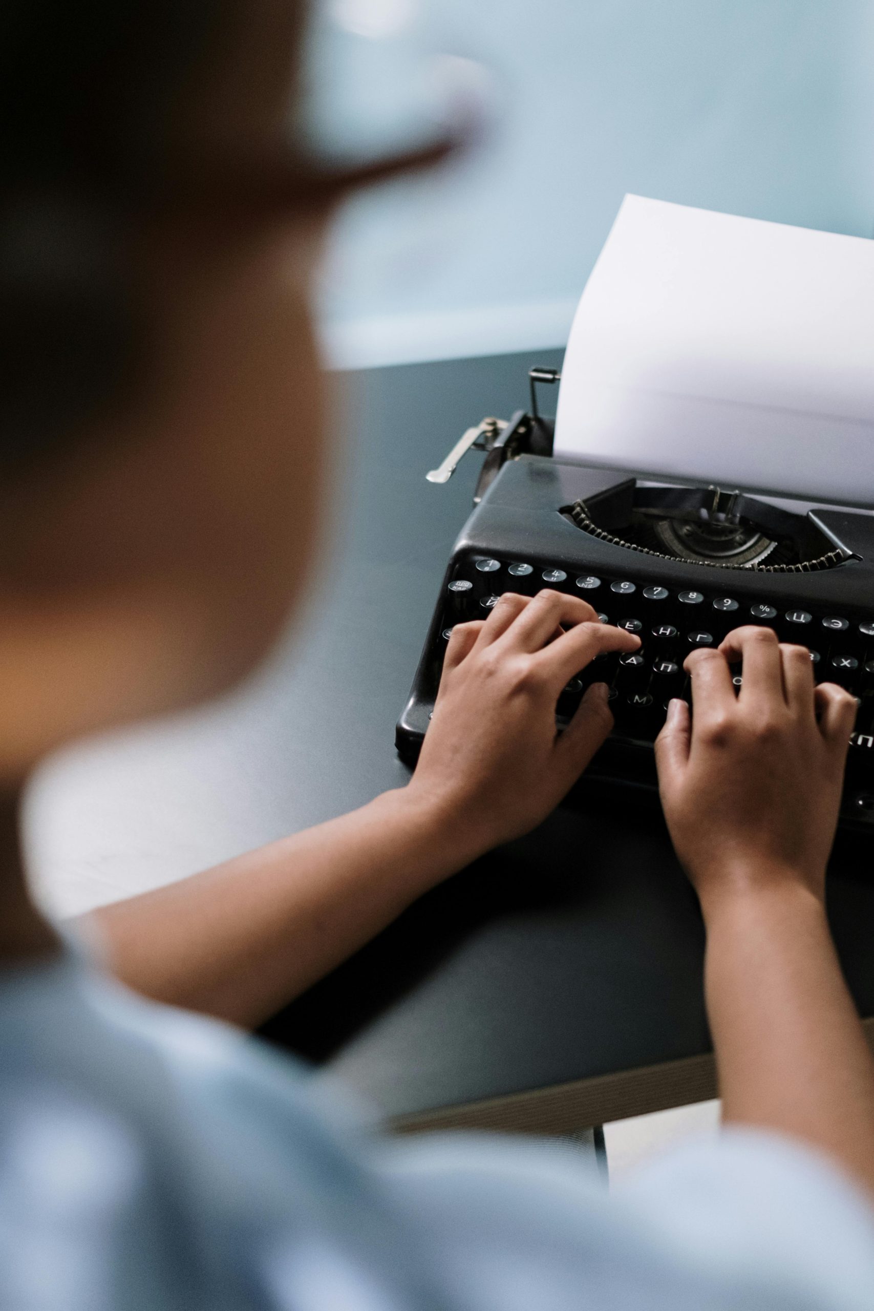 Close-up of hands typing on a vintage typewriter, creating nostalgia.